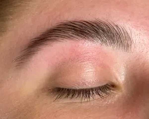 Close-up of a neatly shaped, freshly waxed eyebrow above a closed eye.