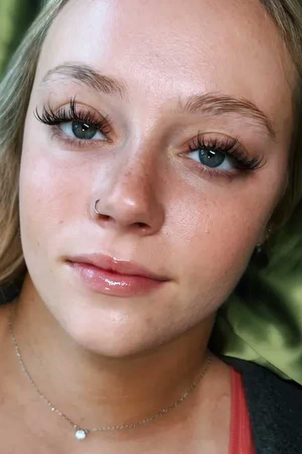 Close-up of a wispy hybrid lash extension set on a client with green eyes.